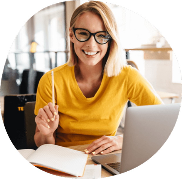 Smiling woman working at a laptop with notebook, reflecting productivity with HubSpot support